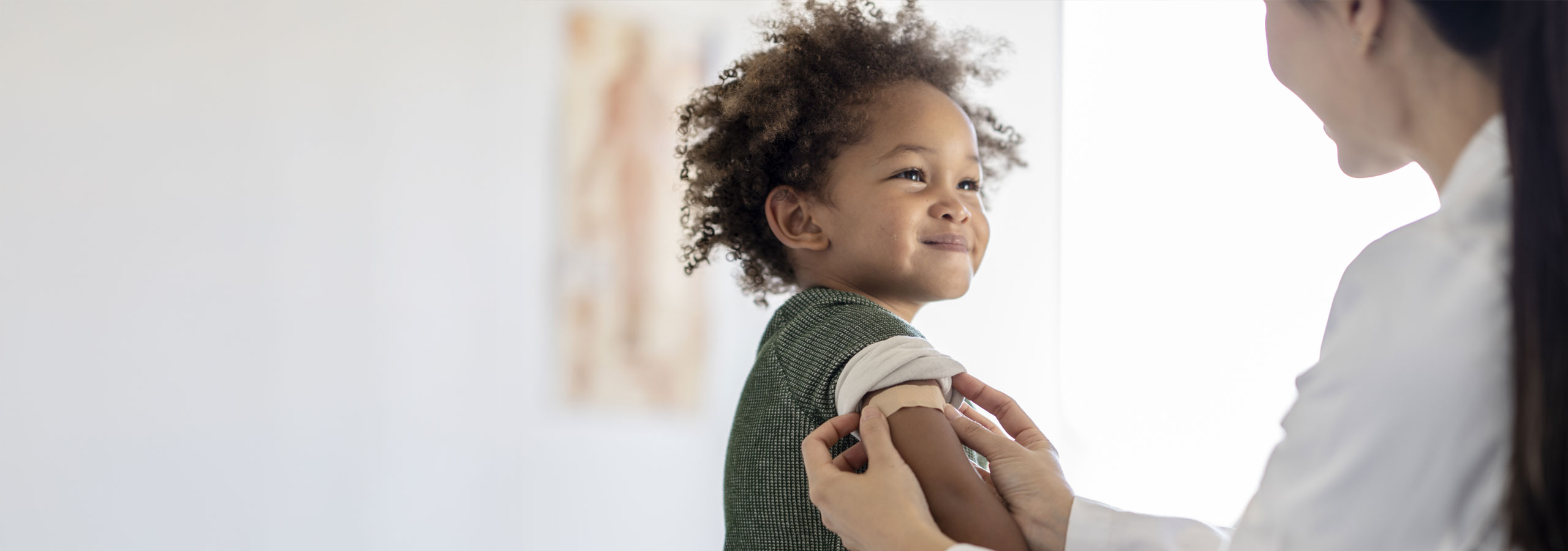 Child getting a band aid from doctor after getting vaccinated
