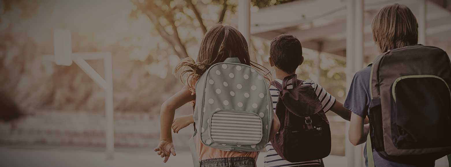 Elementary kids with backpacks on school playground