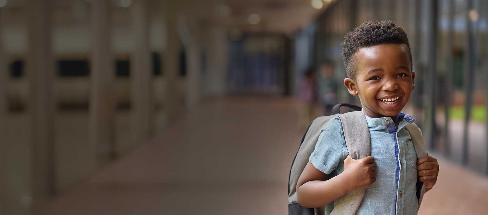 Child with backpack in front of school